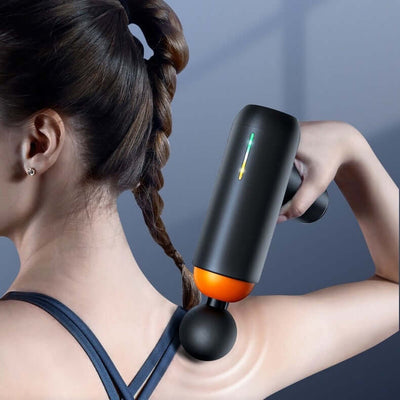 Woman using mini massage gun on shoulder for full body relaxation and recovery.