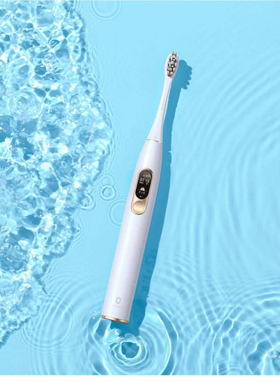 Electric toothbrush designed for maximum cleaning, featuring IPX7 waterproof body and USB charging base in a blue water setting.