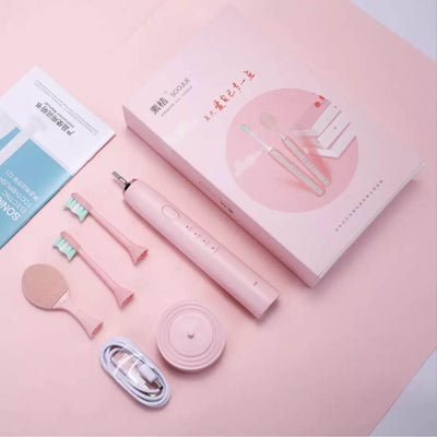 Pink electric toothbrush kit with accessories and packaging on a pastel background.