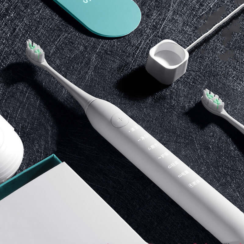 Electric toothbrush with accessories on a black background, showcasing its sleek design and control buttons.