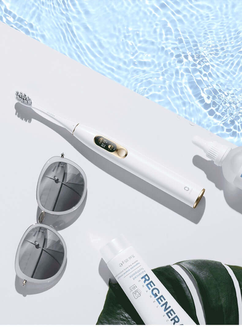 Electric toothbrush beside sunglasses and skincare products on a poolside; features stylish design and waterproof technology.
