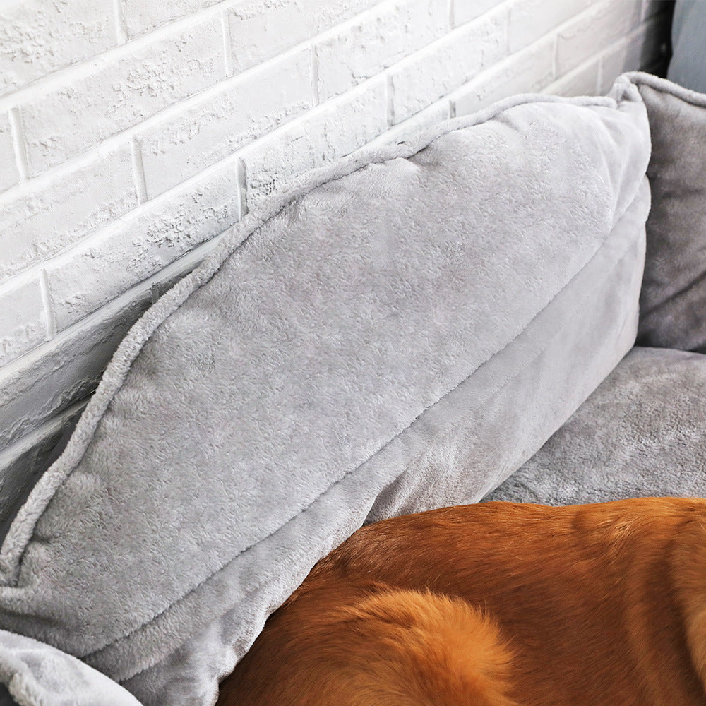 Close-up of a soft gray dog bed with plush cushions, providing comfort for your pet against a white brick wall.