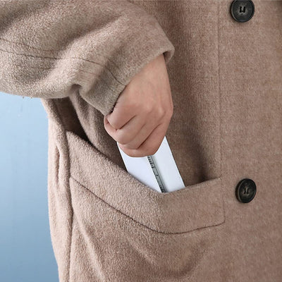 Person placing a portable device into the pocket of a cozy brown coat.