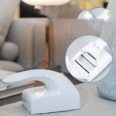 Pet hair remover tool on couch, designed for effective cleaning of cat fur and lint. Contains rotating sticky rollers.