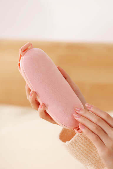 A person holding a pink menstrual massager, designed for pain relief and portable use during menstruation.