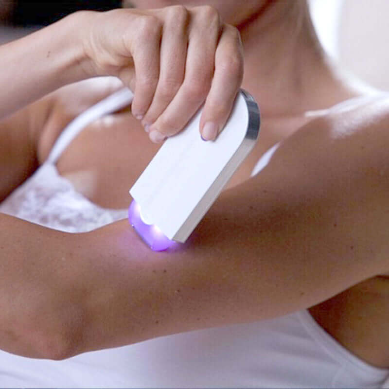 Woman using painless hair remover accessory on her arm, showcasing the product's design and functionality.