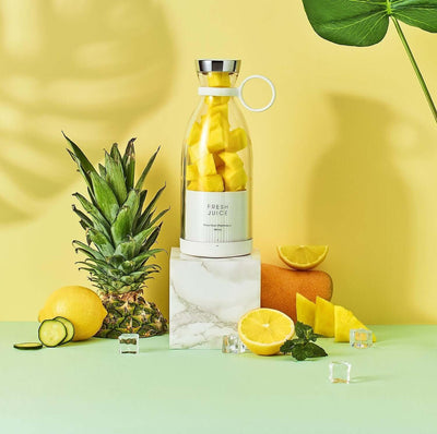 Blender Bottle with fresh fruit including pineapple, lemons, and mango, set against a vibrant background for healthy smoothies.