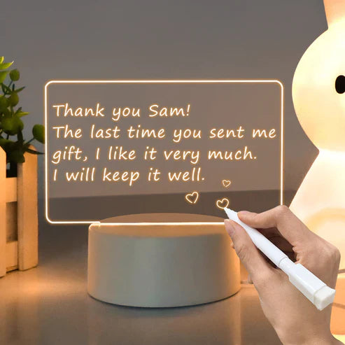 Hand writing a thank you note on an illuminated LED Note Board, showcasing creativity and expression.