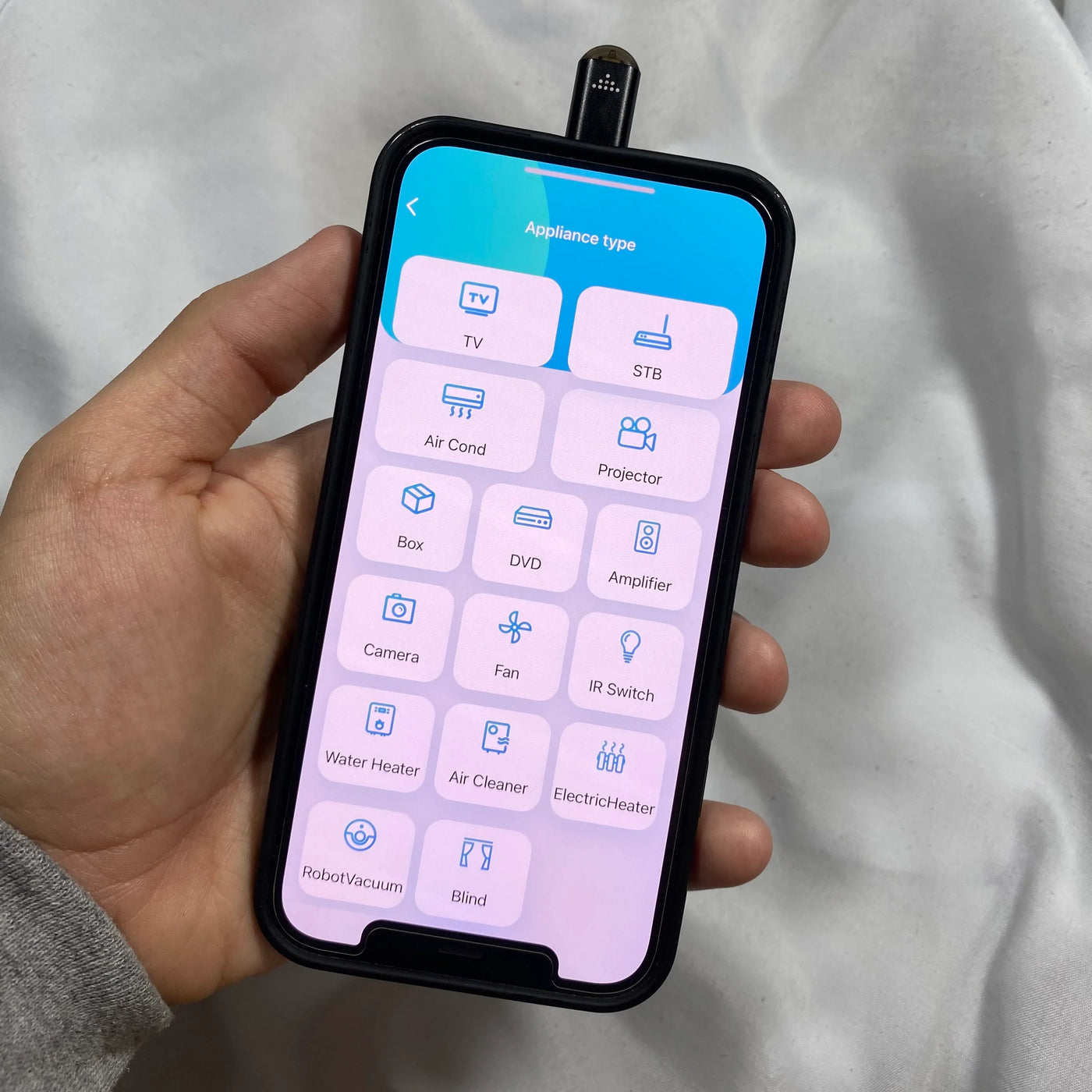 Smartphone displaying app to control various home appliances using an infrared phone adapter.
