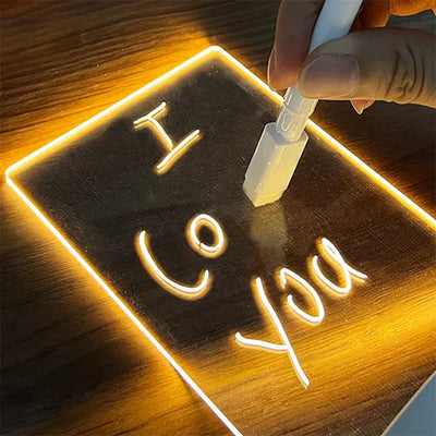 Person writing "I Love You" on an illuminated LED Note Board with a marker.