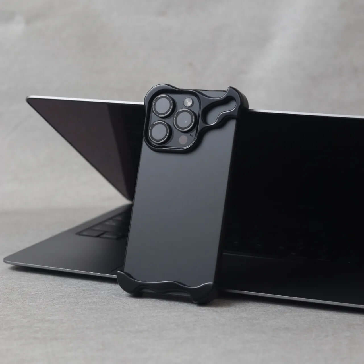 Zinc alloy protective case for iPhone 15 series in Gentlemen Black against a laptop background.