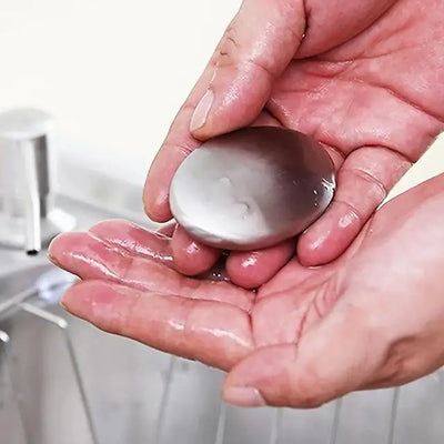 Person holding a shiny steel soap in wet hands, designed to remove cooking odors effectively.